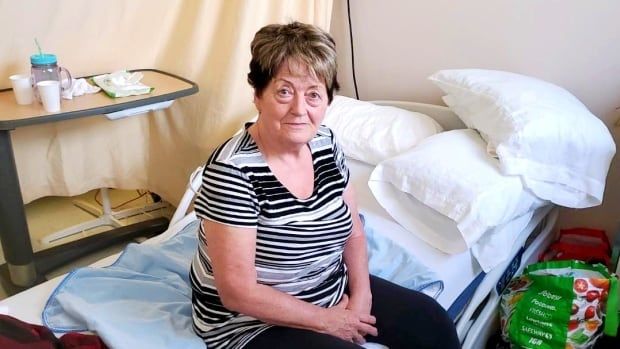 Elderly woman sitting on edge of hospital bed