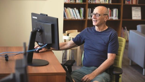 An elderly man smiling at a computer laptop