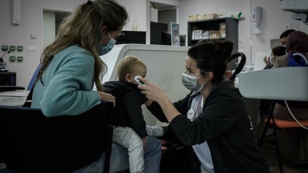 A pediatric unit healthcare worker performs a preliminary health check at the entrance of a hospital.