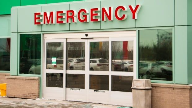 A sign reading "emergency,'' in red letters can be seen above a door on a green building