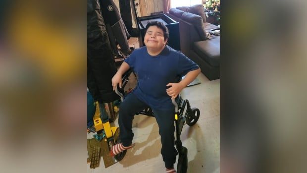 A young boy sits on a walker inside a home.