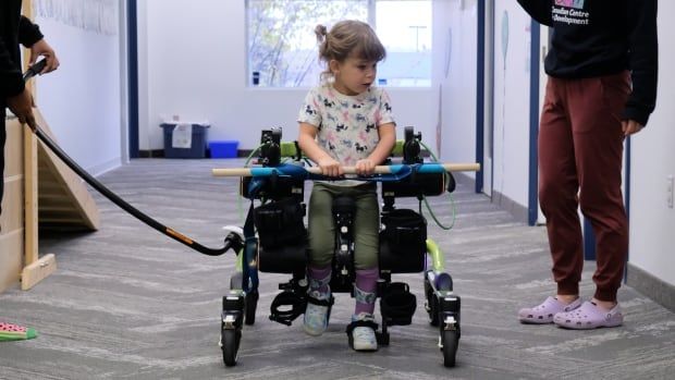 A young girl uses a mechanical device to assist her walking.