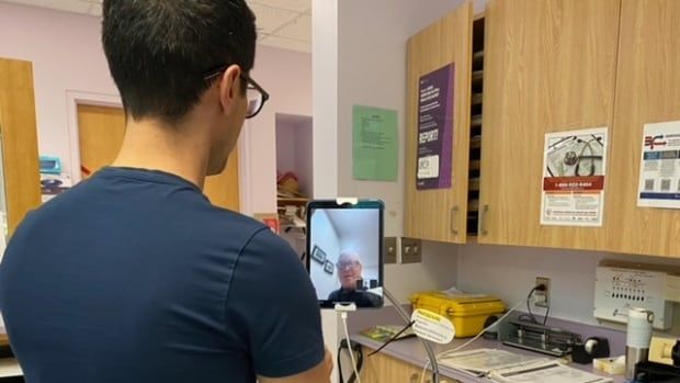 A man speaks to another man over tablet in a hospital. 