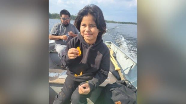 A child is seen sitting on a boat eating chips.