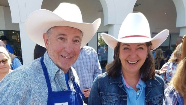 A man and women in cowboy hats smile at the camera. 