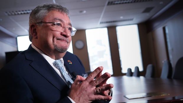 Dr. Horacio Arruda in a blue suit sits in a conference room with his fingertips pressed together.