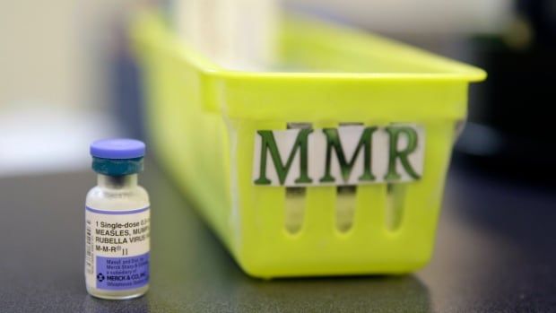 A vaccine vial is shown to the left of a bin labelled "MMR" on a countertop.