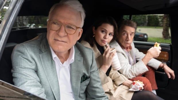 Three people eating In-N-Out Burger look out car window.