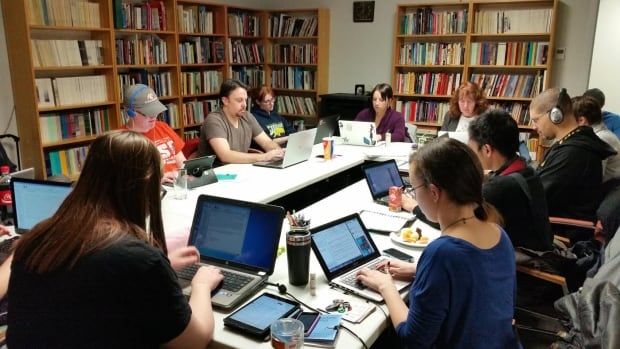 People sit around a table typing on laptops.