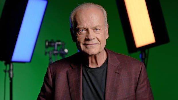 Kelsey Grammer looks at the camera for a picture, while in the background are set lights and a green screen.