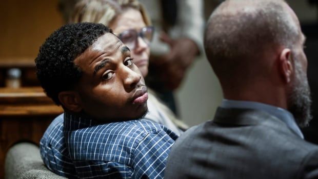 A man looks over his shoulder in a court room.