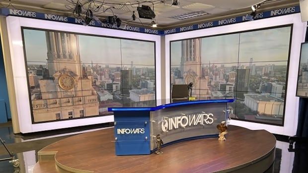 A television studio is shown with a long desk that says Infowars.