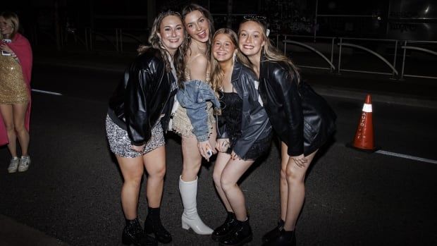 Four young women dressed in sequin outfits outside Rogers Centre, ahead of the Taylor Swift Eras tour concert.