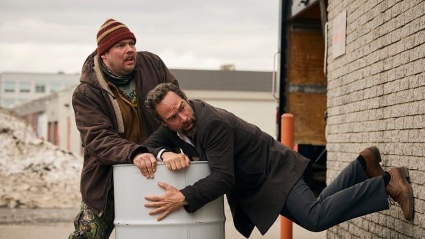 Two men hold onto a barrel. 