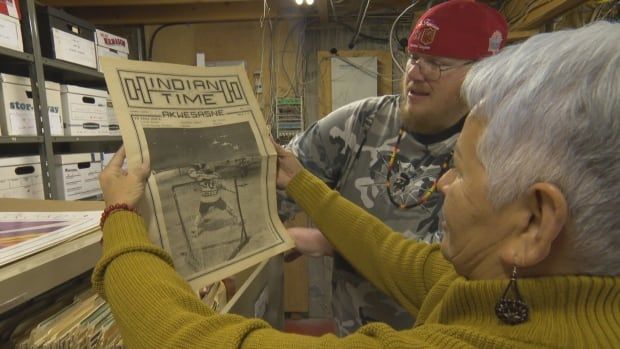 Two people read the front page of an old newspaper from 1983.