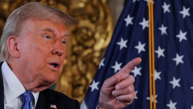 Trump pointing, in front of a US flag