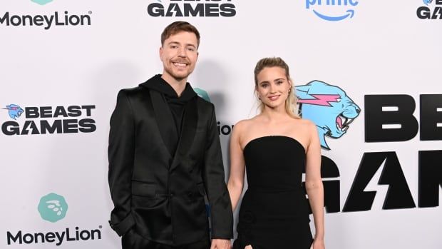 A man and woman are pictured in a suit and dress at a television show premiere. 