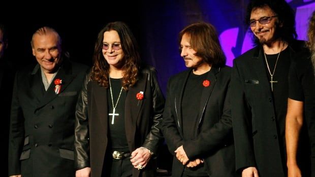 Four men wearing black stand in a lineup together. 