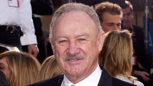 A man with grey hair and a mustache poses in a suit