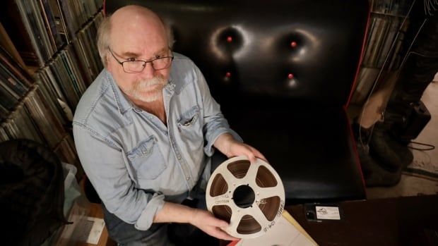 A man holds a recording tape. 