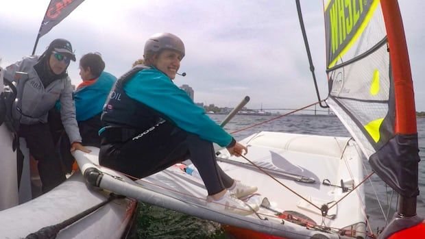 A person in a Waszp sailboat assisted by people on a zodiac. 