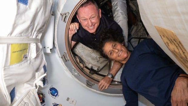 A man and a woman float in a spacecraft with big smiles.