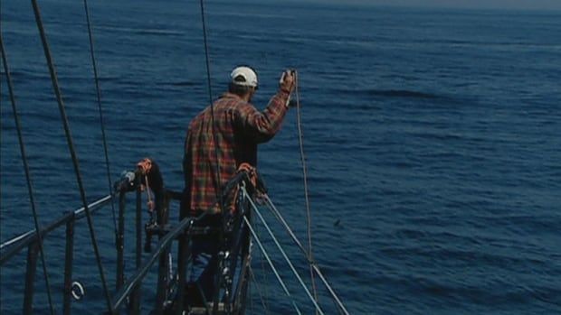 a man stands on the pulpit of a boat witha harpoon in hand. 