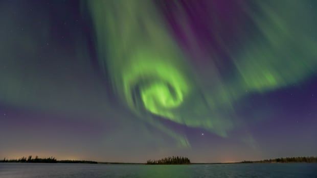 A nighttime shot of a green and purple and blue sky with the island in the middle.