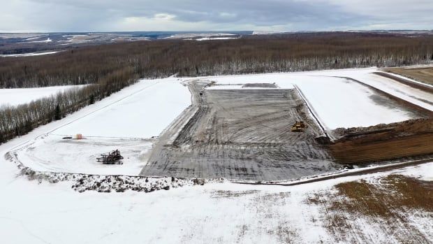 A large, snowy expanse of land cleared for a fracking pad.