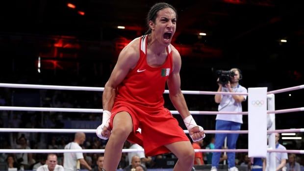 A female boxer is seen celebrating in the ring after a win.