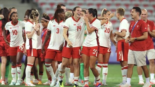 Women's soccer players celebrate after a win.