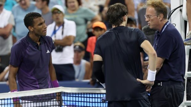 Three men stand around a tennis net.