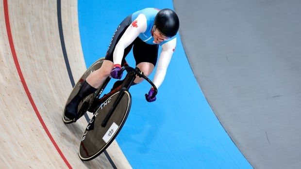 A female track cyclist competing for Canada races around a velodrome.