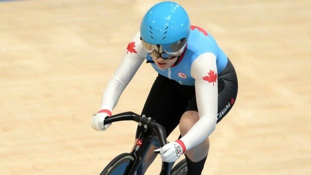 A female Para track cyclist representing Canada races around a velodrome.