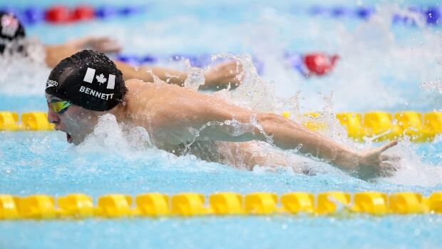 A male Para swimmer takes a deep breath while competing in an individual medley race.