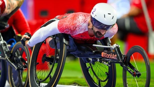 A wheelchair racer pushes forward.