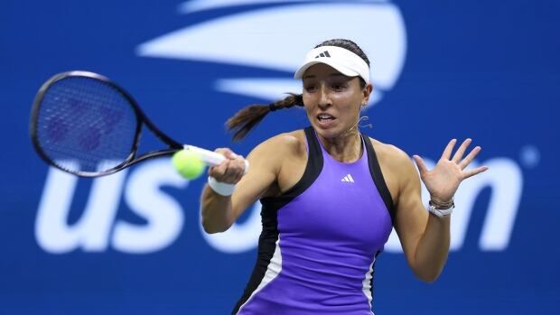 A female tennis player wearing a visor hat returns a shot with a racket in her left hand.