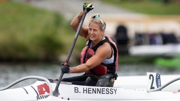 A female Para canoe athlete smiles while paddling through the water in a va'a.