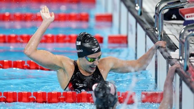 A swimmer raises an arm in the air.