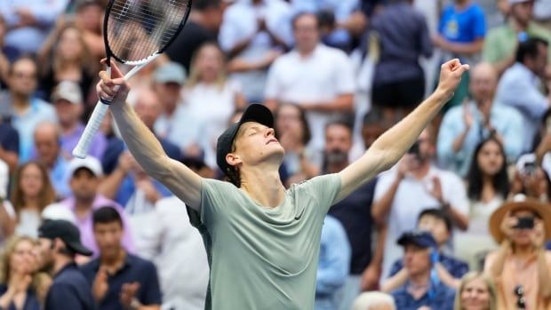 A tennis player lifts his arms in the air.