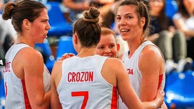 Four Canadian 3x3 basketball women's athletes wearing red and white jerseys huddle on the court during a spot in play at a last-chance Olympic qualifying tournament on May 16, 2024 in Debrecen, Hungary.