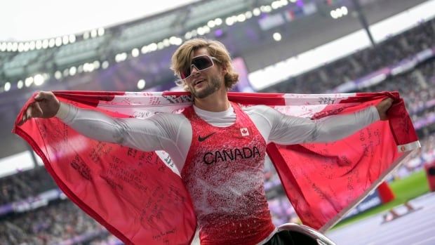 A man in a wheelchair celebrates with a Canadian flag.