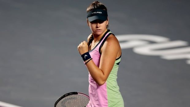 A women's tennis player is shown pumping her fist in celebration.