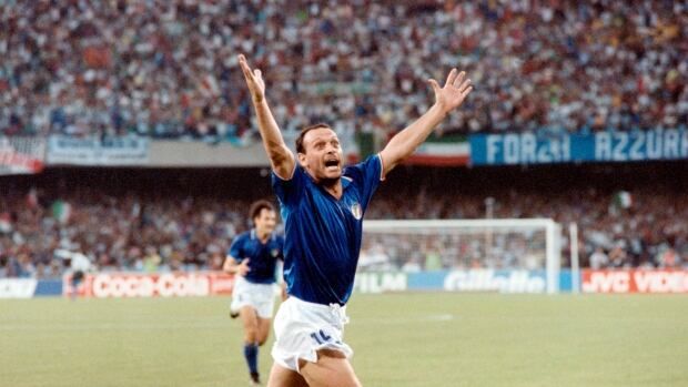 A men's soccer player raises his arms in celebration.