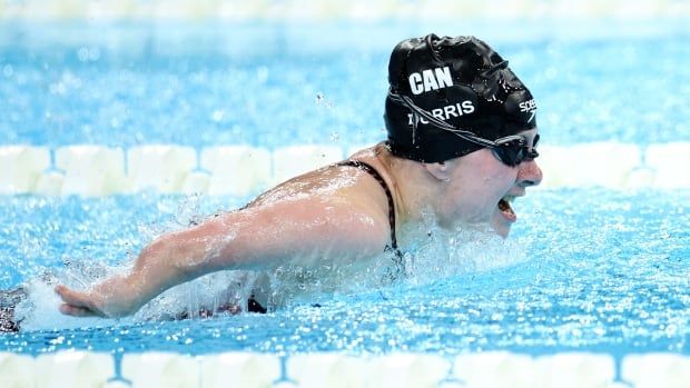 A female Paralympic swimmer takes a breath while racing in a butterfly event.