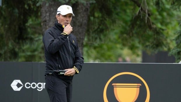 A male golfer places his right hand on his chin while standing on a course.