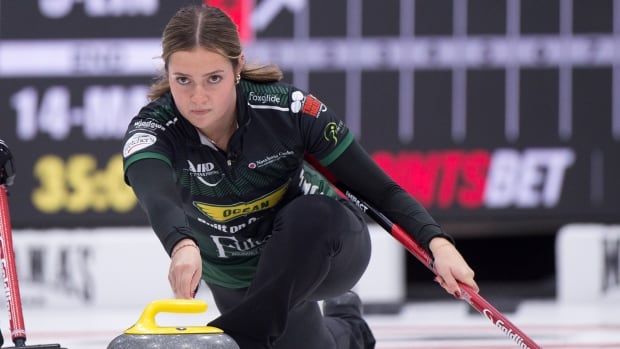 A female curling skip delivers a stone with her right hand.