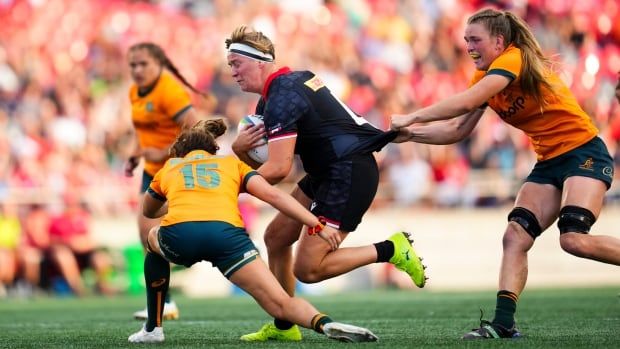 A female rugby player is seen being tackled mid-game.