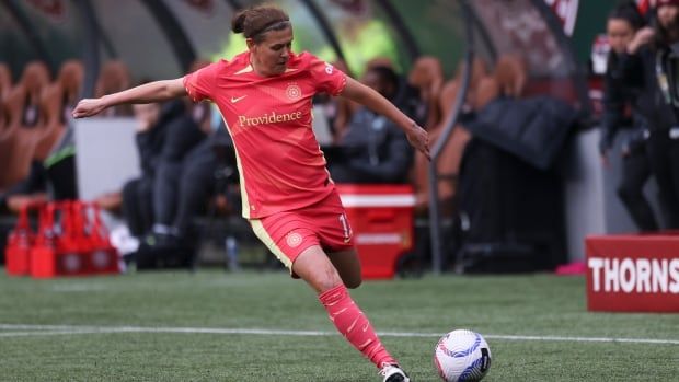 A female soccer player winds up to kick the ball with her left leg during a match.