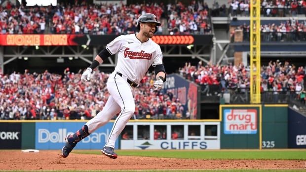 A male baseball player is seen running past the bases and celebrating.